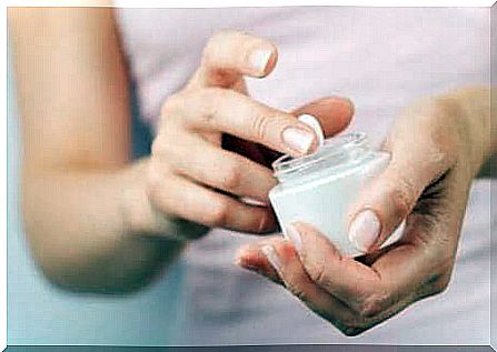 A woman dabs her finger in a cream.