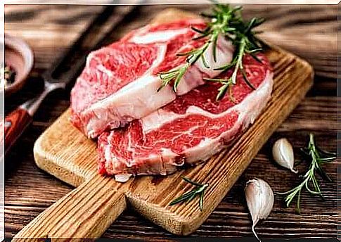 Slices of red meat on a cutting board with garlic and rosemary